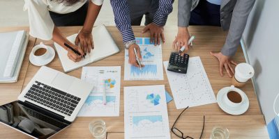 Coworkers analyzing charts and graphs at the meeting, view from above